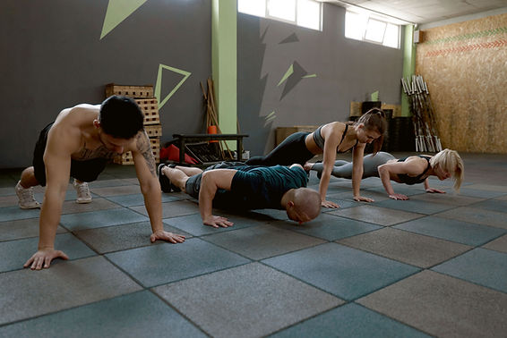 Four people in a gym doing push-ups